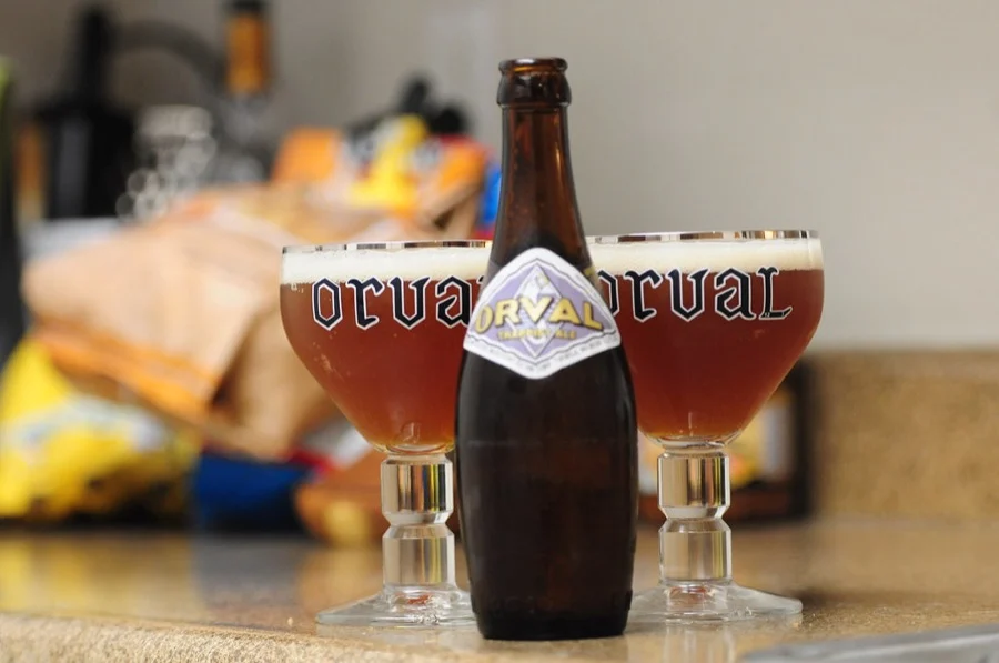 Bouteille d'Orval entre deux verres calices remplis de bière cuivrée